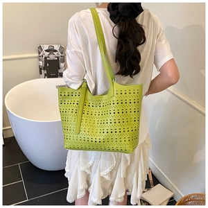 Détail d'un grand sac cabas vert fluo ajouré au laser avec motifs géométriques et bandoulières