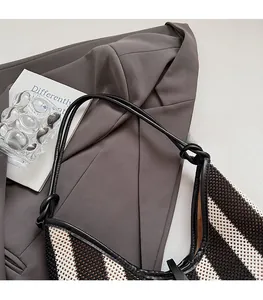 Detail shot of black and white striped knit tote bag texture on a dark grey suit