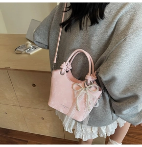 Détail du sac seau en similicuir rose avec nœud en dentelle et perles de mode