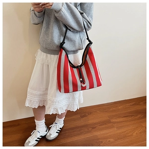 Detailed view of red and white striped woven tote with black knotted leather strap