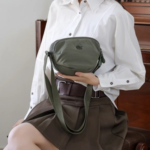 Detailed view of olive green nylon saddle bag with layered zippers and adjustable strap