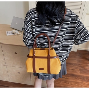 Dettaglio di una borsa a secchiello in tela gialla indossata con finiture in pelle caramello