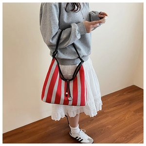 Detail of red and white striped knit hobo bag with black leather shoulder strap