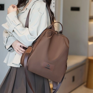 Dettaglio dello zaino marrone in nylon minimalista con logo MIKEDA su una modella