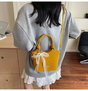 Modèle portant un sac seau jaune en cuir avec dentelle blanche et perles