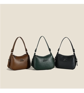 Detailed close-up of textured leather shoulder bags in brown, green and black with metal logo