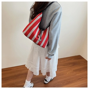 Detail view of red striped mesh tote bag featuring black drawstring closure and strap