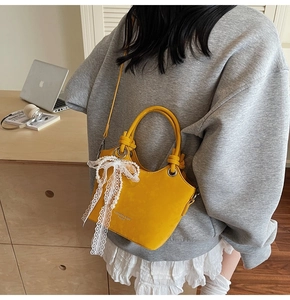 Détail du sac seau jaune avec nœud en dentelle et perles porté par un mannequin