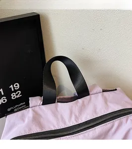 Detail of the durable black webbing handle and smooth zipper on a purple outdoor backpack