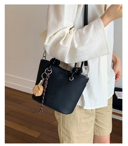 Close-up of black lychee leather bucket bag with knot handle and gold hardware