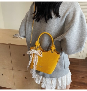 Détail du sac seau jaune avec nœud en dentelle, breloque perle et poignée nouée