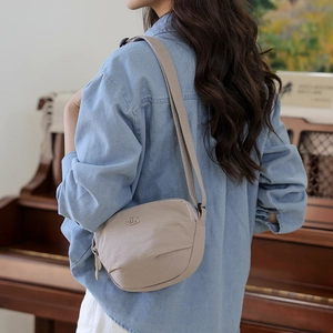 Detail of light beige nylon crossbody bag with adjustable wide strap and minimal logo