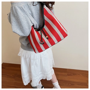 Detail of red and white striped knit tote bag with black leather handle and silver rings