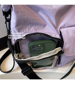 Detail view of purple nylon crossbody bag with clear zipper pocket and green smartphone