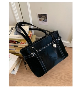 Detail shot of black glossy tote bag featuring silver eyelet buckles and a heart charm