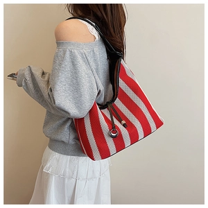 Detail of red and white striped woven tote bag with drawstring and black straps on a model