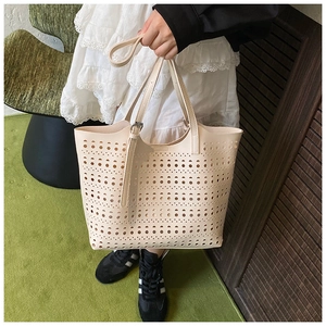 Détail des motifs géométriques découpés au laser sur un grand sac cabas crème avec sangle