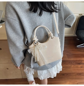Détail du sac seau crème avec nœud en dentelle et perle et texte Fashion & Bags