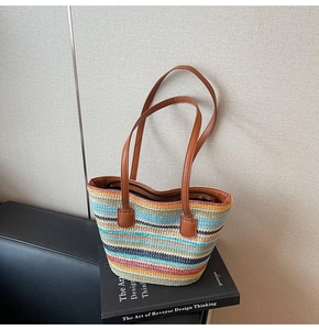Macro view showing the colorful woven straw texture and reinforced brown leather handles