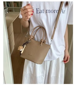 Detail shot of khaki lychee leather bucket bag with top handles and adjustable strap