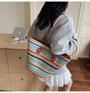 Detail of colorful striped woven tote bag with brown leather handles on a female model