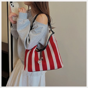 Detail of red and white striped knit hobo bag with black leather strap and silver pendant