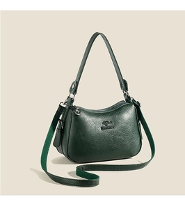 Detailed view of dark green pebbled leather shoulder bag with gold kangaroo emblem