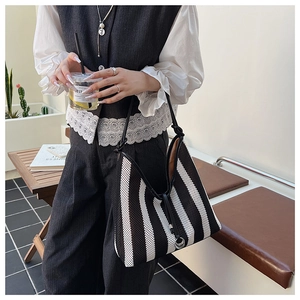 Detail of black and white striped mesh tote bag with silver ring shoulder strap