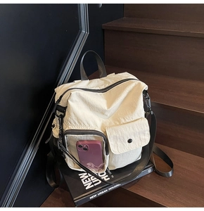 Detail view of cream nylon travel backpack with a transparent pocket on wood stairs