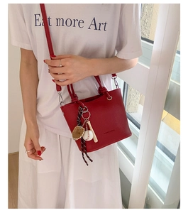 Detail of red pebbled leather handbag featuring unique baseball glove and bat charms