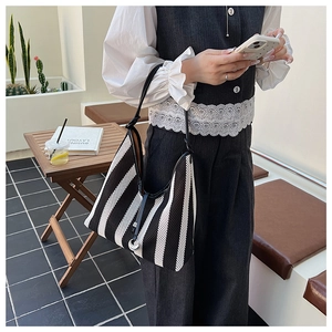 Detail of a black and white striped woven tote bag featuring a knotted shoulder strap design