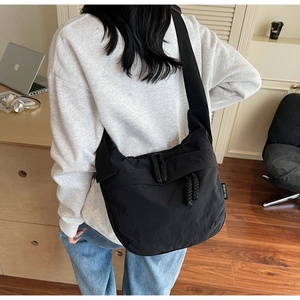 Detail of black crossbody dumpling bag with woven zipper pull and woven label detail