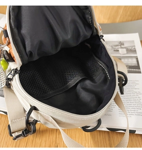 Detail view of the cream crossbody bag interior featuring black mesh compartment storage