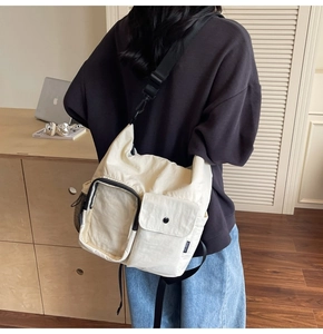 Detail of a functional beige multi-pocket crossbody bag with black adjustable strap