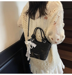 Détail du sac seau noir avec nœud en dentelle blanche et chaîne en perles sur l'escalier