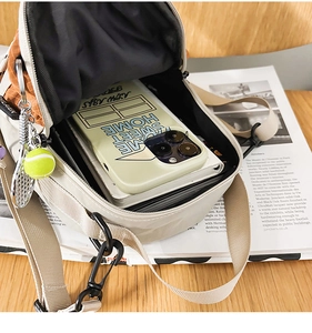 Detailed interior of a beige canvas crossbody bag showing phone and notepad storage capacity