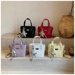 Five textured faux-crocodile bucket bags in various colors on minimalist stone steps