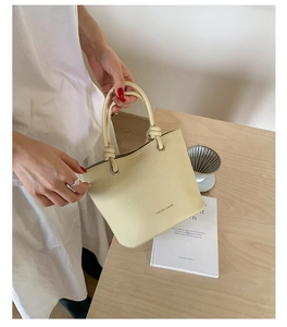 Detail of cream leather handbag with knotted handles and fashion text in a lifestyle setting