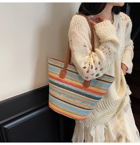 Detail of colorful striped straw tote bag showing vibrant woven texture and brown leather strap