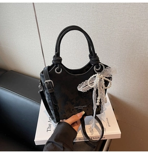 Détail du sac seau noir mat avec des charms élégants en perles et dentelle blanche