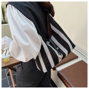 Close-up of black and white striped mesh tote bag with black leather shoulder straps