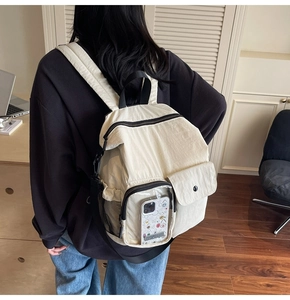 Detail of a beige nylon backpack with multiple pockets and a transparent front window