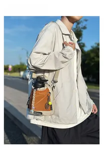 Detail of outdoor crossbody bag with drawstring closure and tennis racket charm accessory