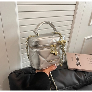 Dettaglio borsa vanity argento trapuntata con catena dorata e ciondoli a cuore