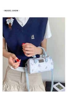Detailed view of light blue Boston bag with bear prints and silver metal logo plate