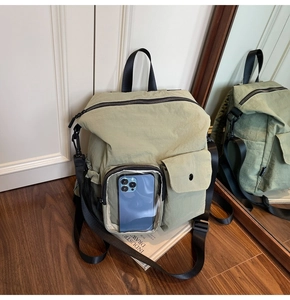 Detail of light green hiking backpack with transparent front pocket for smartphone storage