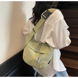 Sage green nylon crescent crossbody bag with wide adjustable strap worn by model