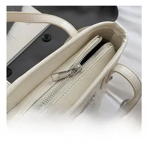 Detail of silver balloon dog pendant and croco-embossed texture on cream bucket bag