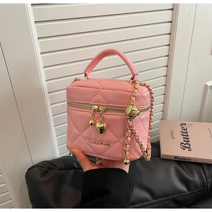 Dettaglio della borsa a secchiello rosa trapuntata con ciondoli a cuore e tracolla a catena