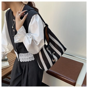 Detail of black and white striped mesh tote bag featuring textured grid fabric and side drawstring